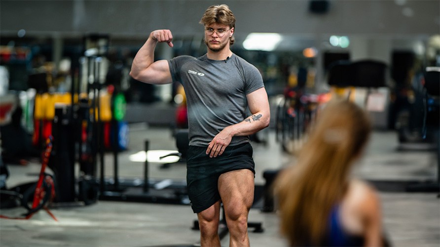 Dreng i fitnesscenter, der spnder sine ben og arme.